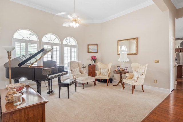 sitting room with ceiling fan, light colored carpet, ornamental molding, and a wealth of natural light