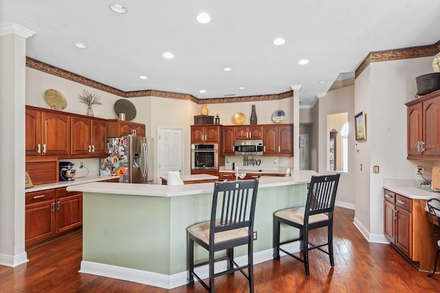 kitchen featuring a breakfast bar, dark wood-type flooring, a spacious island, crown molding, and appliances with stainless steel finishes