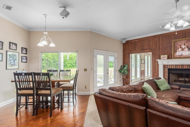 living room with a brick fireplace, wood-type flooring, and ornamental molding