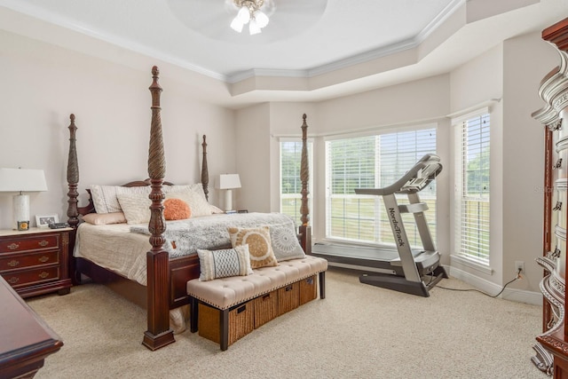 bedroom featuring ornamental molding, a tray ceiling, ceiling fan, and light colored carpet