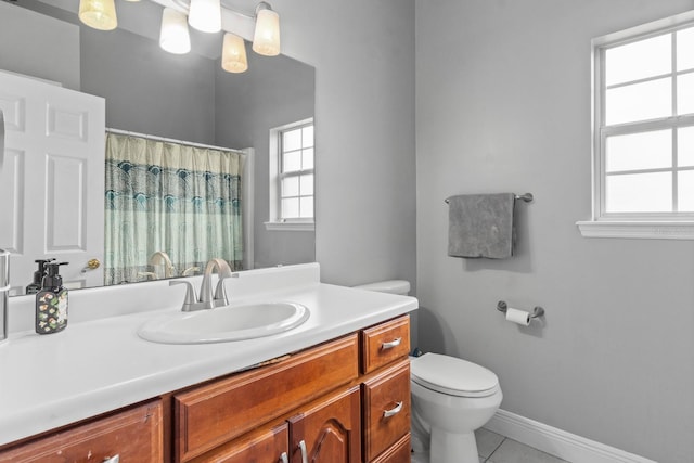 bathroom with tile patterned floors, vanity, a healthy amount of sunlight, and toilet