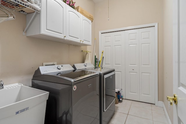 laundry area with washer and dryer, light tile patterned floors, cabinets, and sink