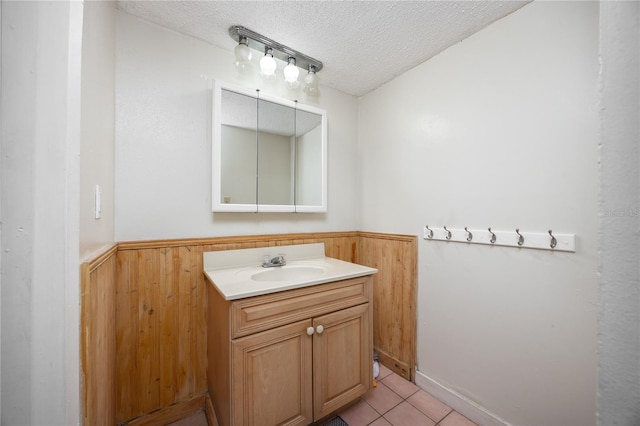 bathroom with vanity, a textured ceiling, tile patterned floors, and wood walls