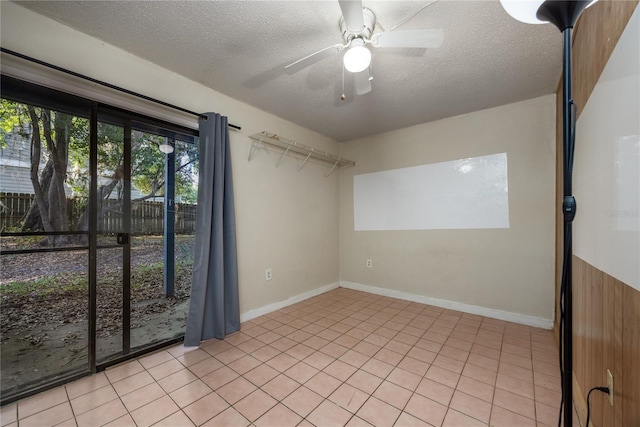 unfurnished room with ceiling fan, light tile patterned floors, and a textured ceiling