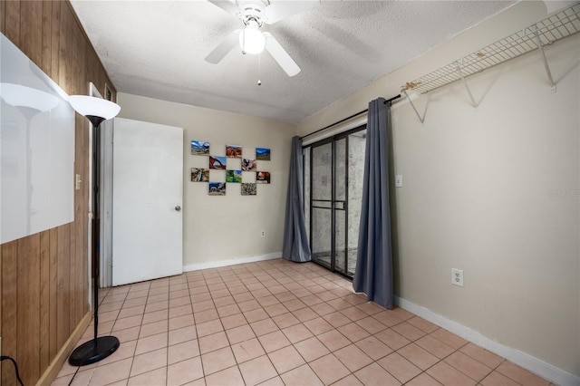 spare room featuring ceiling fan, light tile patterned flooring, a textured ceiling, and wooden walls