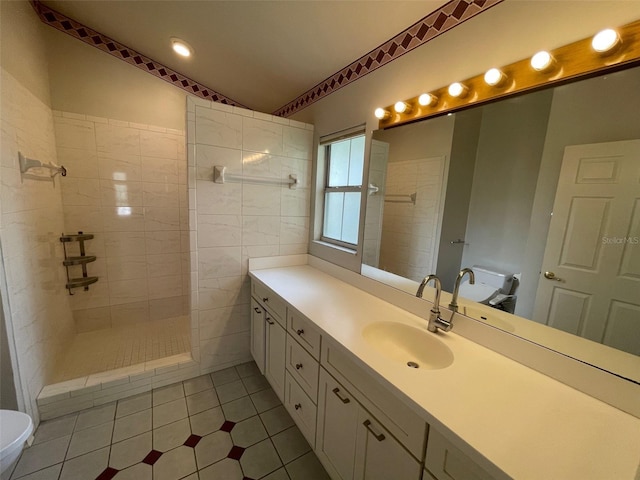 bathroom with a tile shower, vanity, tile patterned flooring, and toilet