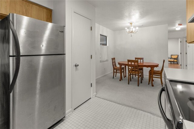 kitchen with a notable chandelier, light colored carpet, stainless steel fridge, and range with electric cooktop