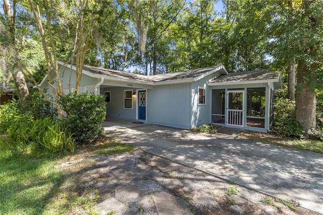 ranch-style home with a carport, driveway, and a sunroom