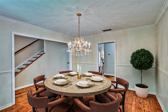 dining area featuring wood-type flooring, crown molding, and a notable chandelier