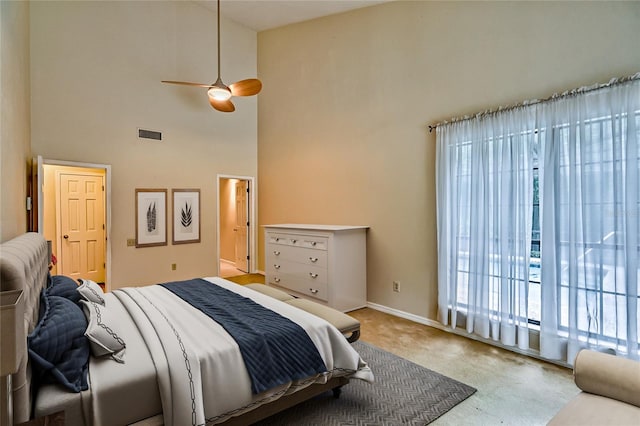 carpeted bedroom featuring ceiling fan, access to exterior, and a high ceiling