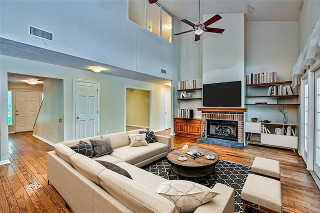 living room featuring a fireplace, high vaulted ceiling, hardwood / wood-style flooring, and ceiling fan