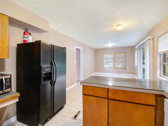 kitchen featuring black refrigerator with ice dispenser and light tile patterned flooring