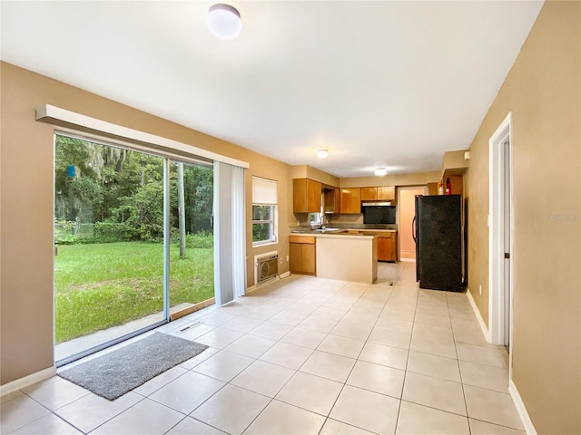 kitchen with light tile patterned flooring, sink, and black fridge