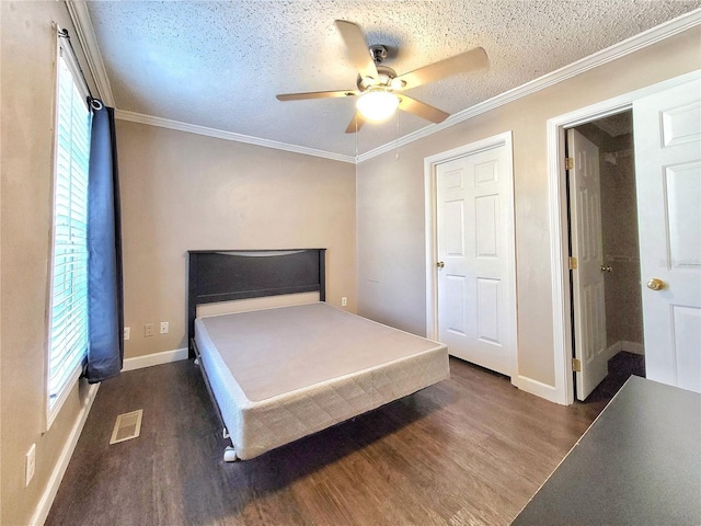 bedroom featuring ceiling fan, dark hardwood / wood-style flooring, a textured ceiling, and ornamental molding