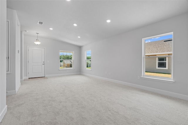 spare room featuring lofted ceiling and light carpet