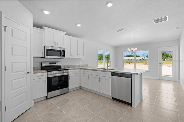 kitchen with white cabinets, decorative light fixtures, stainless steel appliances, and kitchen peninsula