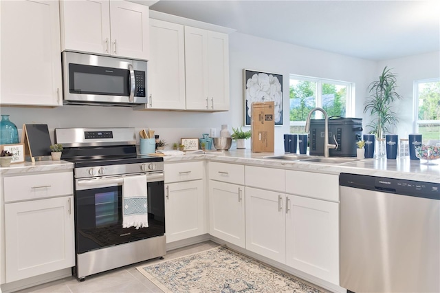 kitchen featuring a healthy amount of sunlight, white cabinetry, sink, and stainless steel appliances