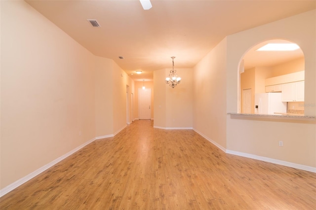 empty room with light hardwood / wood-style floors and an inviting chandelier