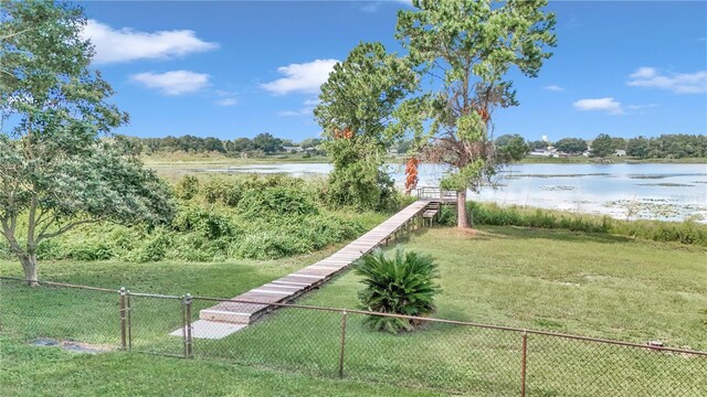 view of home's community featuring a lawn, fence, and a water view