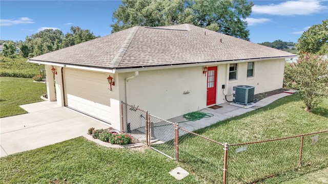 ranch-style home with a front lawn, fence, concrete driveway, central AC, and stucco siding