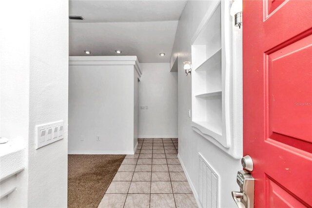 entryway with light tile patterned floors, visible vents, light carpet, and baseboards