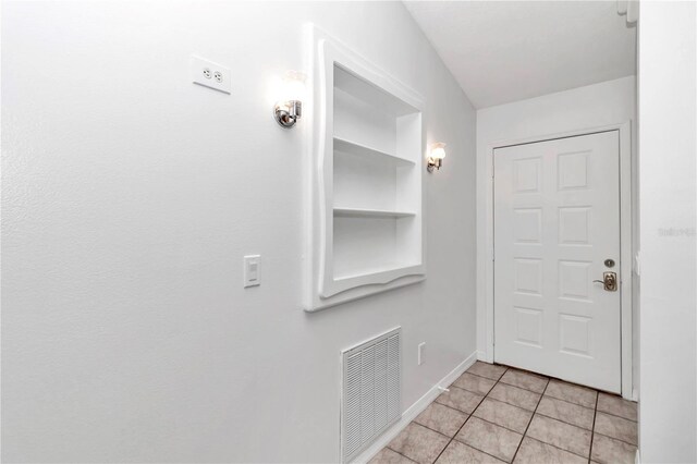 interior space featuring light tile patterned flooring, visible vents, built in shelves, and baseboards