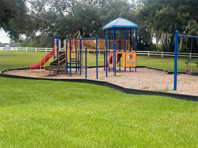 community play area featuring a lawn and fence