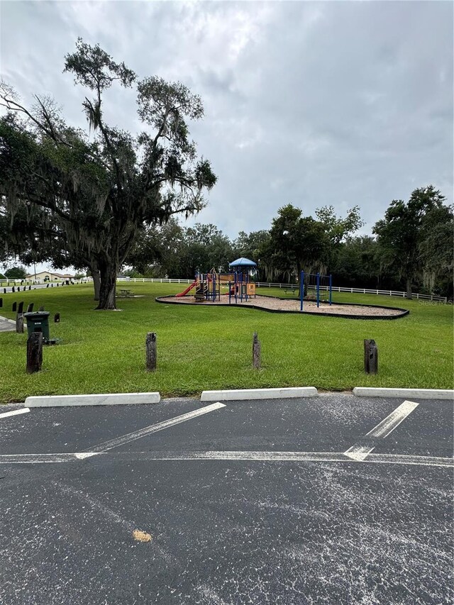 exterior space with playground community, a yard, and uncovered parking