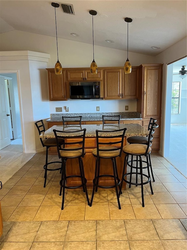 kitchen featuring visible vents, pendant lighting, a breakfast bar, and vaulted ceiling