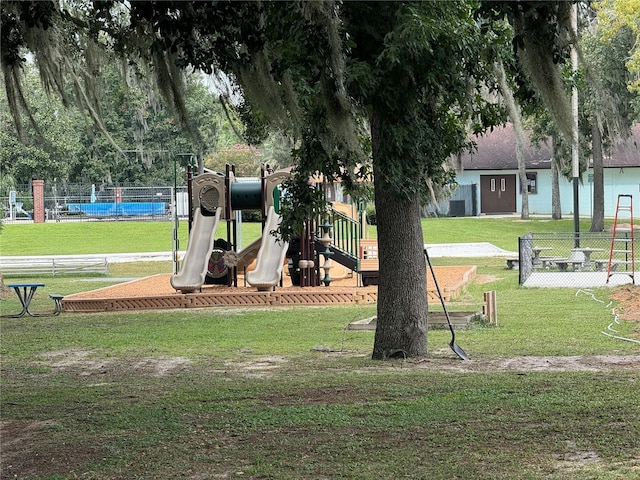 view of home's community with fence, a lawn, and playground community