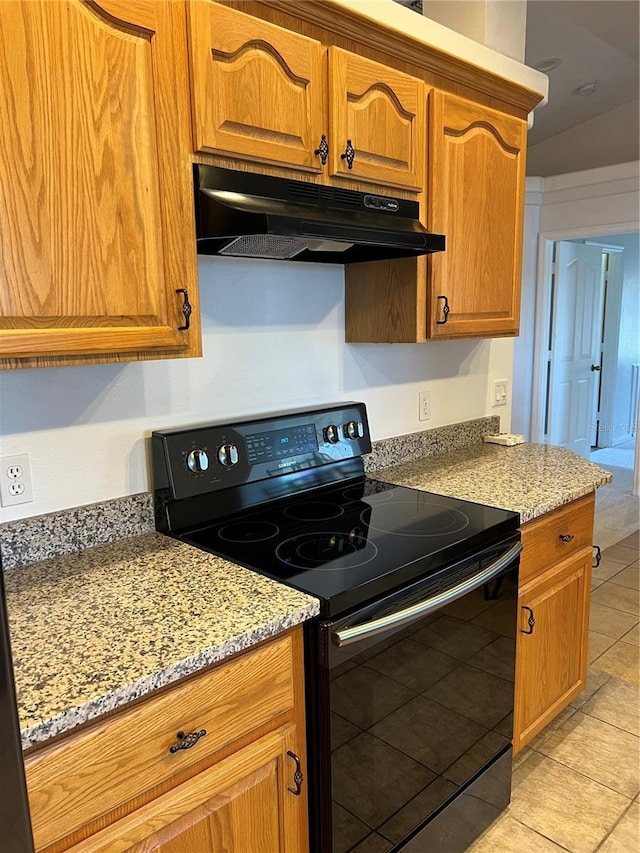 kitchen featuring light tile patterned floors, brown cabinetry, light stone countertops, black range with electric cooktop, and under cabinet range hood