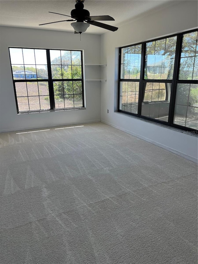 carpeted spare room featuring a ceiling fan and baseboards