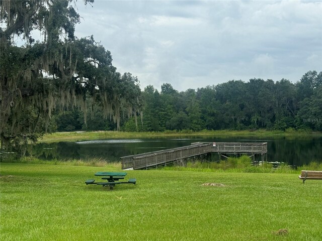 surrounding community featuring a wooded view, a lawn, and a water view