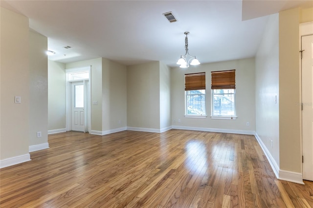 unfurnished room with hardwood / wood-style floors and a chandelier