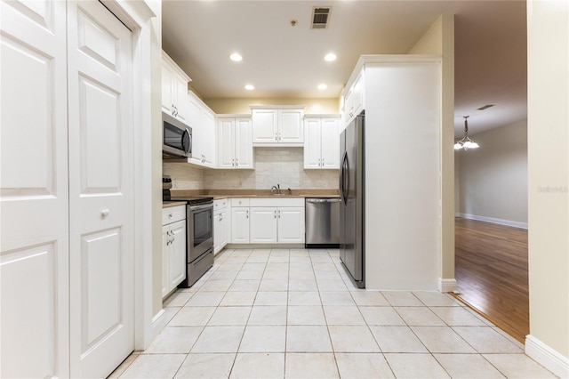 kitchen featuring tasteful backsplash, white cabinets, stainless steel appliances, and light hardwood / wood-style floors