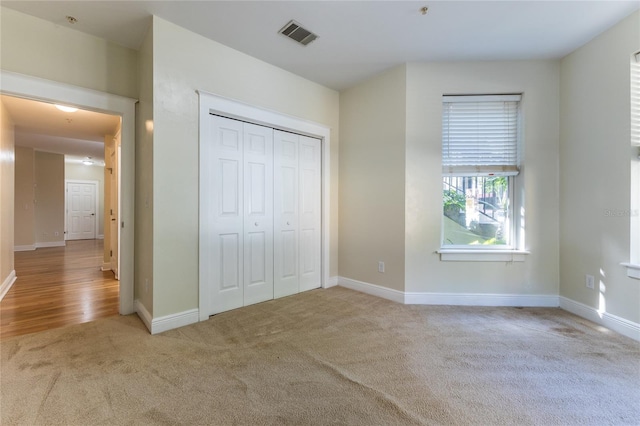 unfurnished bedroom with a closet and light colored carpet