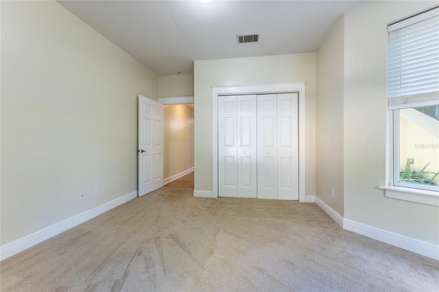 unfurnished bedroom featuring a closet and light colored carpet