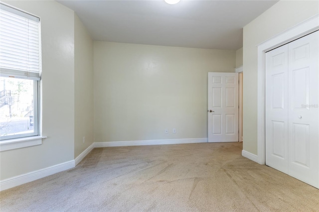 unfurnished bedroom featuring a closet and light colored carpet