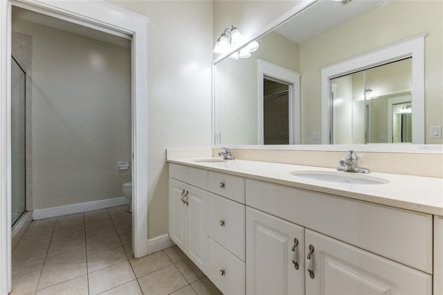 bathroom featuring toilet, vanity, tile patterned floors, and a shower with door