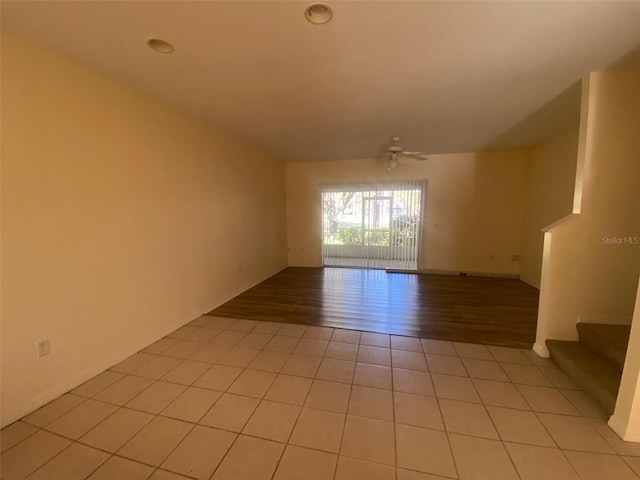 unfurnished room with stairway, light tile patterned floors, and a ceiling fan