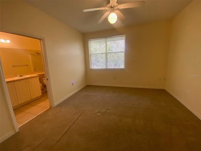 unfurnished bedroom featuring light carpet, baseboards, vaulted ceiling, and ensuite bath