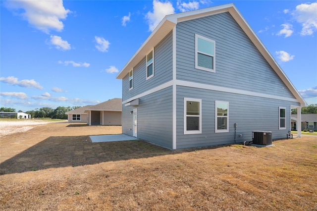 rear view of house featuring central air condition unit, a lawn, and a patio