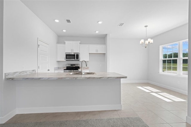 kitchen featuring white cabinetry, sink, light stone counters, decorative light fixtures, and appliances with stainless steel finishes