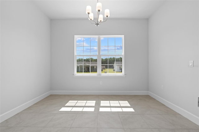 empty room with an inviting chandelier and light tile patterned flooring