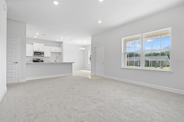 unfurnished living room featuring light carpet, sink, and a chandelier