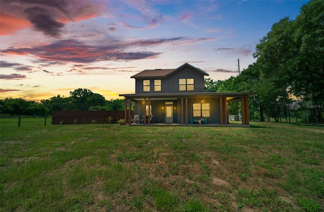 back house at dusk with a yard and a porch