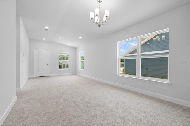 spare room with light carpet, an inviting chandelier, and vaulted ceiling