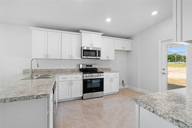 kitchen with white cabinets, appliances with stainless steel finishes, light tile patterned flooring, and sink