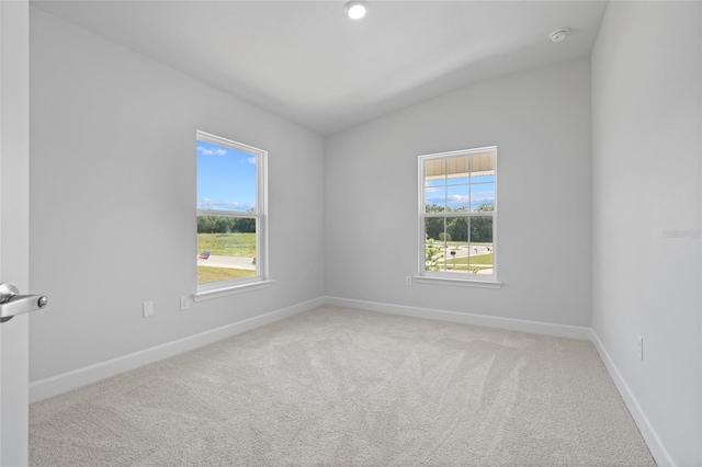 carpeted spare room featuring plenty of natural light and vaulted ceiling