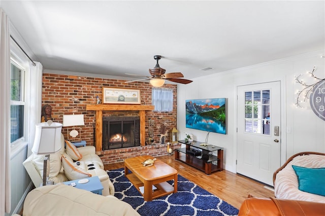 living room with crown molding, a fireplace, ceiling fan, and light hardwood / wood-style floors